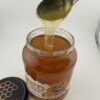 Tekutý květový med VysočinaMed.cz stékající ze lžíce do sklenice 1 kg
